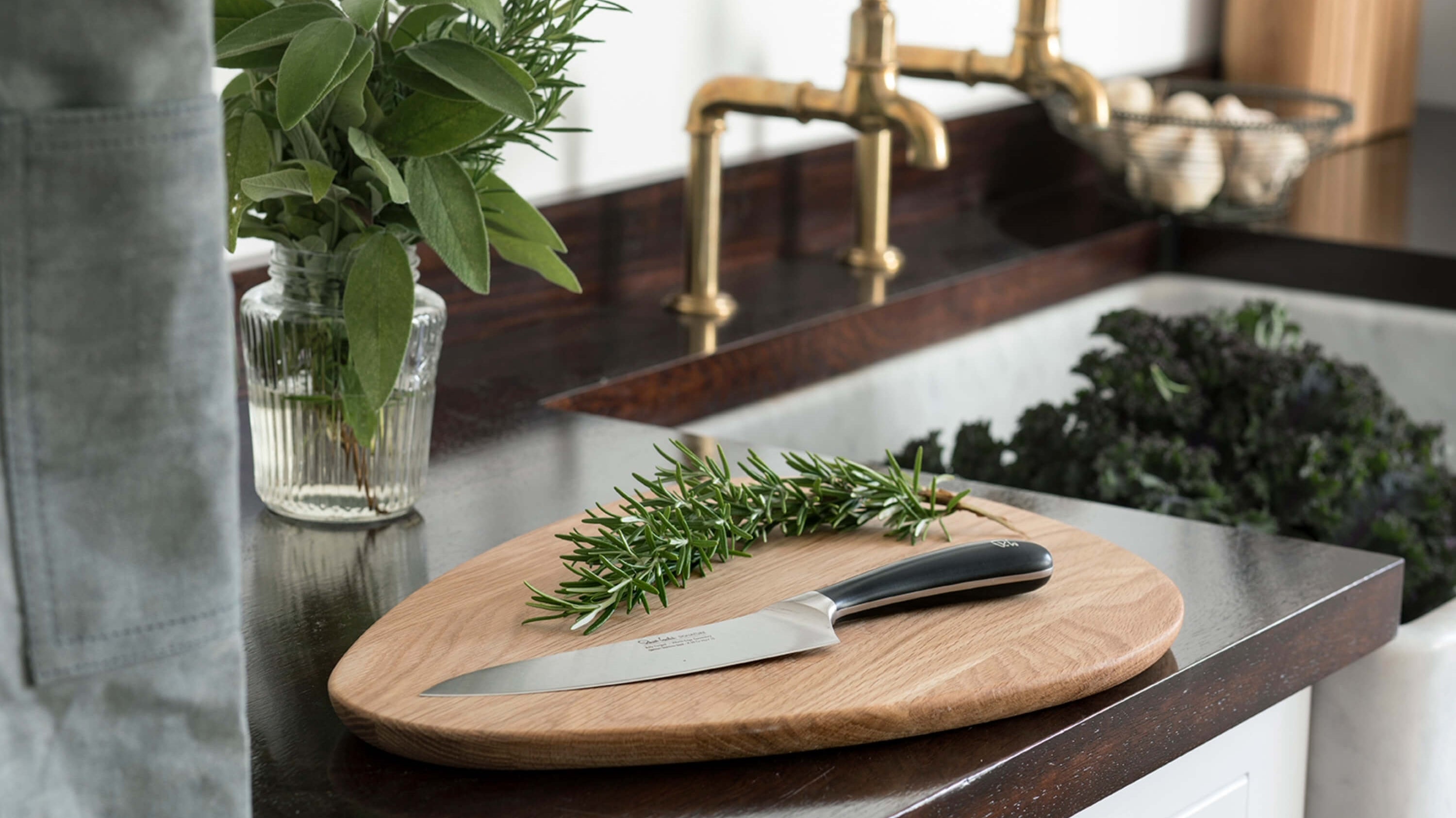 En äggformad skärbräda i högkvalitativt ekträ från Robert Welch med en kökskniv ur Robert Welch Signature-serie på.