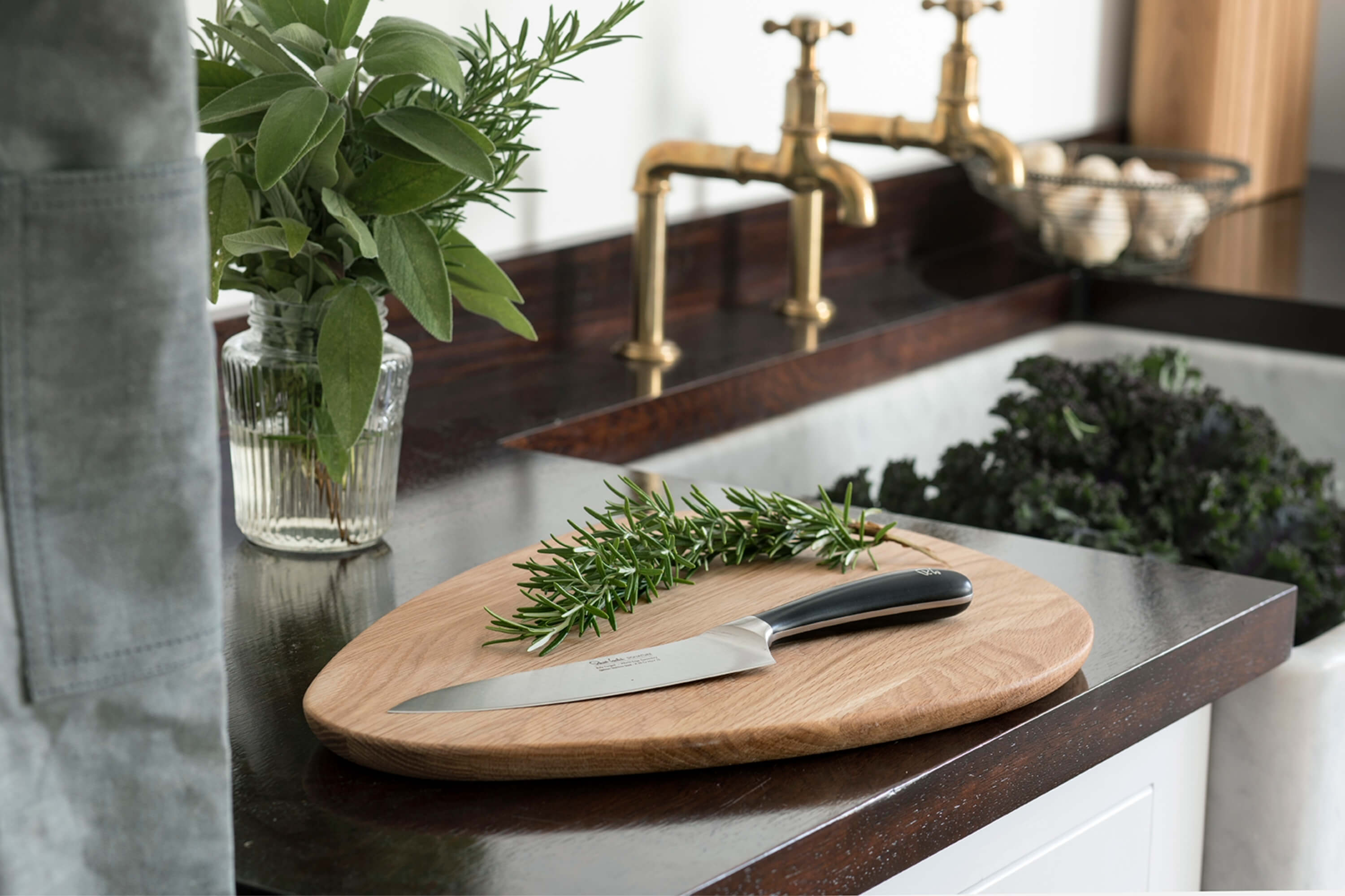 En äggformad skärbräda i högkvalitativt ekträ från Robert Welch med en kökskniv ur Robert Welch Signature-serie på.